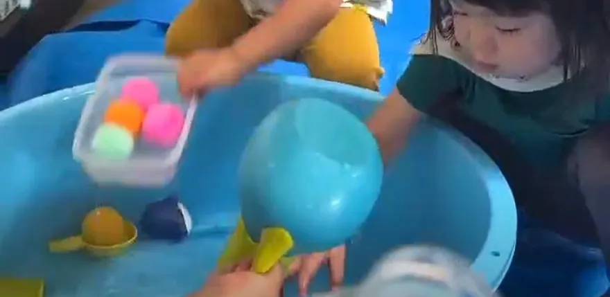 水をはったタライでボールなどを使って水あそびをする子どもたち